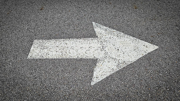 istock White painted arrow on asphalt road surface, representing direction and navigation in transportation contexts. 2228195974