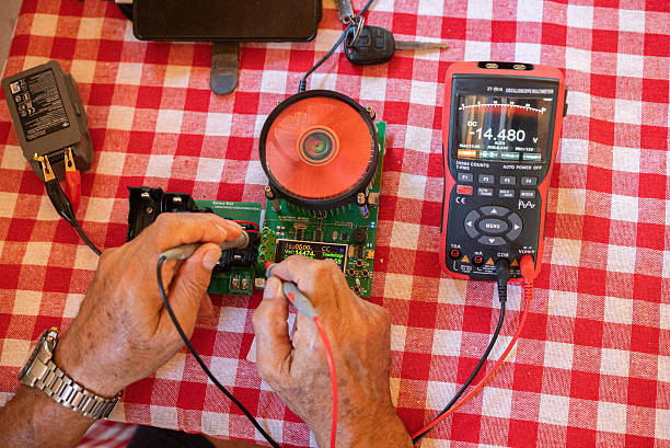 Yellow digital multimeter with probes for measuring voltage, resistance on grey background, a multimeter is an electronic measuring instrument.