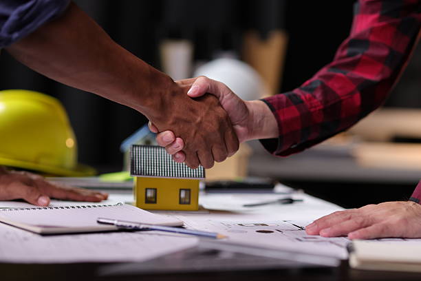 istock Architect and engineer shaking hands after closing a deal. Two man shaking hands over a house project with blueprints. 2228199881