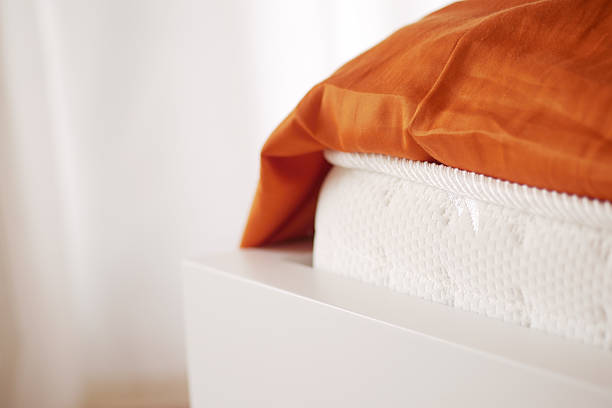 istock Cozy bedding view featuring an orange blanket and white mattress 2228202310