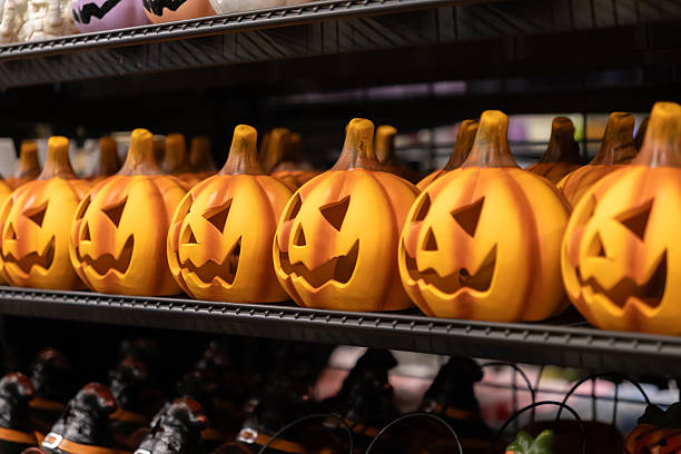 istock Orange Halloween pumpkin decorations with spooky carved faces are neatly displayed on a store shelf, symbolizing festive seasonal sales and autumn celebration 2228204842