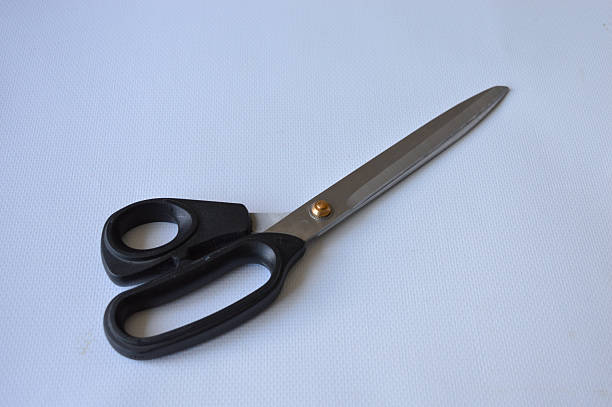 istock hand holding large metal scissors with black handle ideal for themes like sewing, crafting, cutting, DIY projects, tailoring, textile work, or home office supplies 2228205607