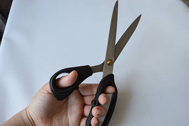 istock hand holding large metal scissors with black handle ideal for themes like sewing, crafting, cutting, DIY projects, tailoring, textile work, or home office supplies 2228205634