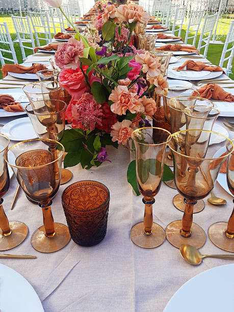istock Table set for an event party or wedding reception. Close-up of glassware on a table decorated for a garden event. Detail of floral centerpieces and tableware prepared for celebrations. Catering 2228205818