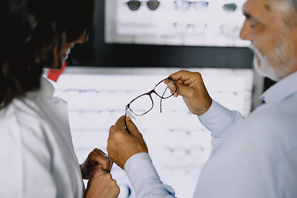 istock Young female optometrist assisting an elderly male client in choosing eyeglass frames at a modern optical store. 2228209738