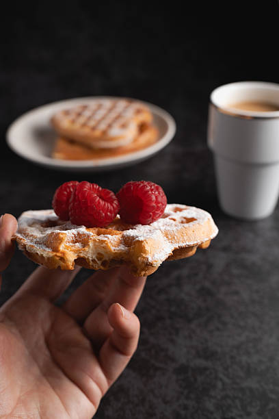 istock Hand holding a freshly baked waffle with raspberries 2228209914
