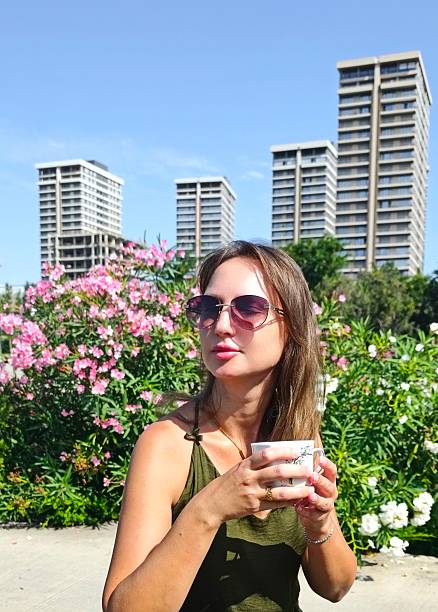 Close-up of an young Caucasian woman drinking iced coffee on a beach during her vacation