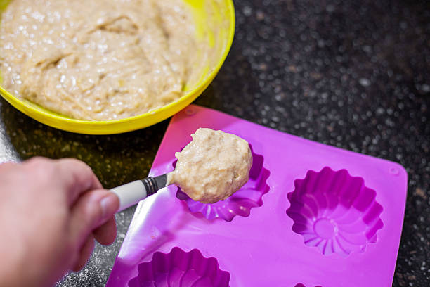 istock A hand spoons batter into a purple silicone mold in preparation for baking muffins 2228217233