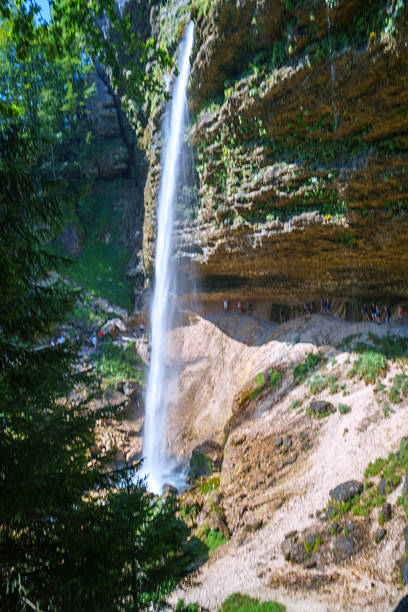 Big waterfall called Pericnik which falls from the cascade in Triglav National Part, Slovenia. In backgroundin cave path with some tourists, watching the waterfall.