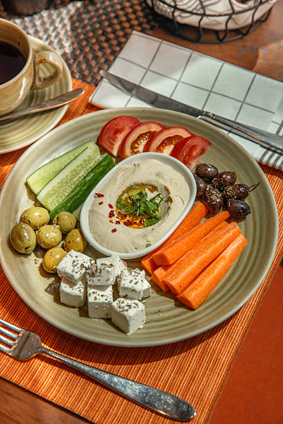 Arabic Middle Eastern breakfast food snack with hummus and vegetable sticks crudite , feta cheese and olives served in hotel restaurant