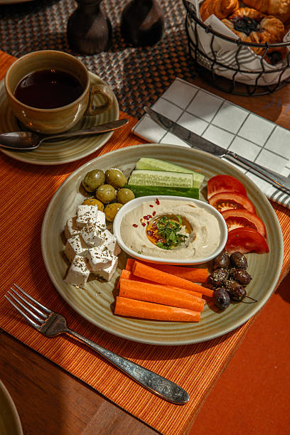 Arabic Middle Eastern breakfast food snack with hummus and vegetable sticks crudite , feta cheese and olives served in hotel restaurant