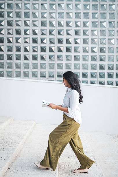 istock Young woman walking up stairs while reading a book 2228229037