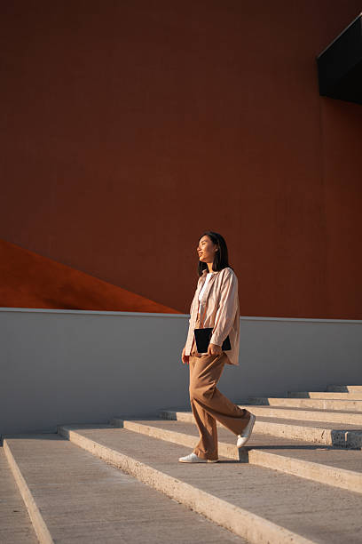 Young professional walking down stairs holding tablet in urban setting