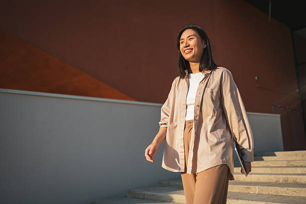 istock Smiling young woman walking down stairs holding tablet 2228229050