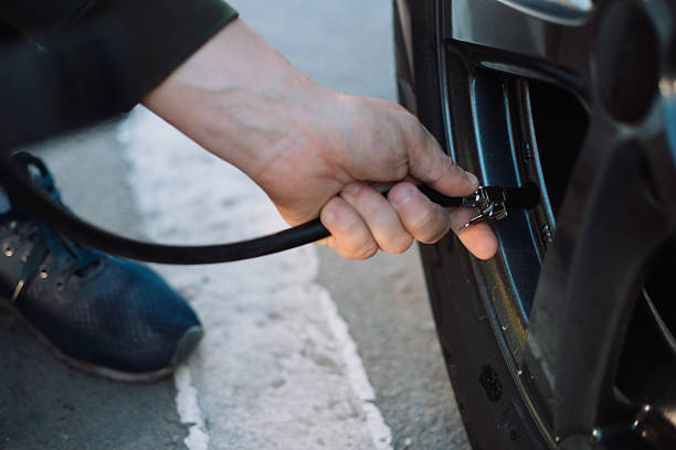 istock Person's hand inflating a car tire with an air compressor, checking pressure 2228231004