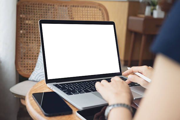 istock Mocktp laptop on table. Woman using and typing on laptop computer with blank white desktop screen on wooden table in coffee shop, rear view. 2228233084