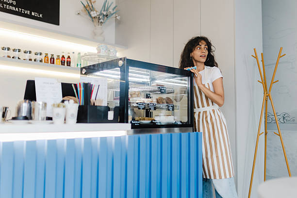 istock Woman Working in Bakery Standing Next to Display Counter with Cakes 2228233098