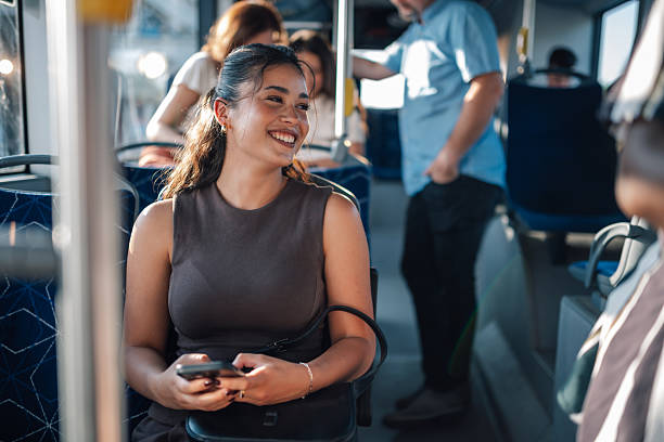 istock Young woman smiling while riding the bus and using her smartphone 2228233786