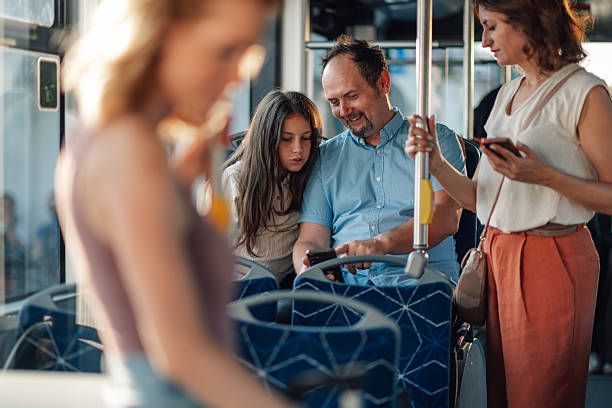 istock Father and daughter using smartphone on bus while mother stands nearby 2228233806