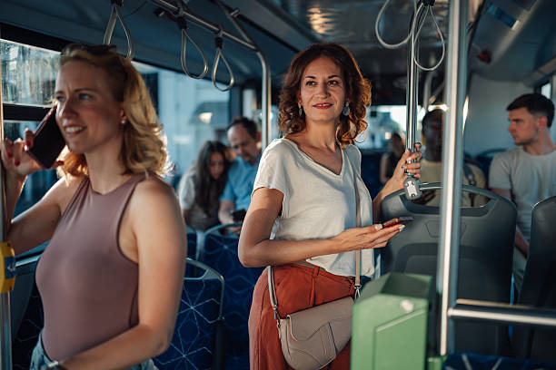 istock Woman standing on a bus holding smartphone and looking away while other passengers sit 2228233813