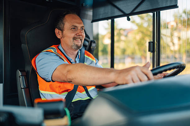 istock Smiling bus driver steering modern city bus on sunny day 2228233887
