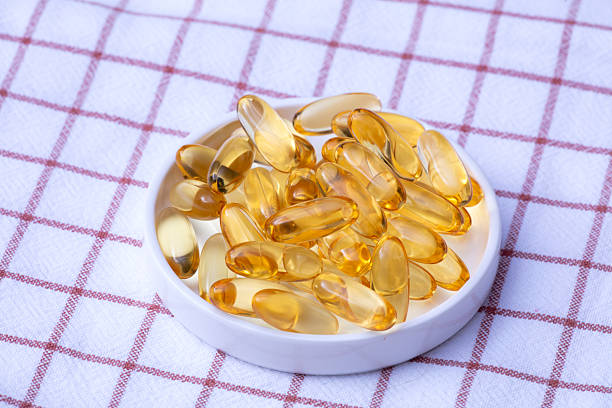White ceramic bowl filled with golden capsules placed on a red checkered fabric background.