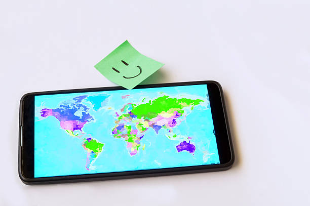 Mobile phone with a world map and a post-it note with a smile in green on a white background