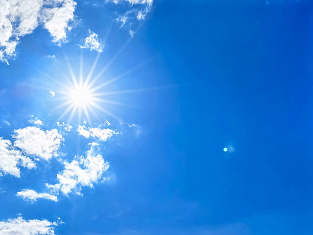 istock Bright sun with beautiful sunbeams shining through a clear blue sky with wispy clouds 2228238736