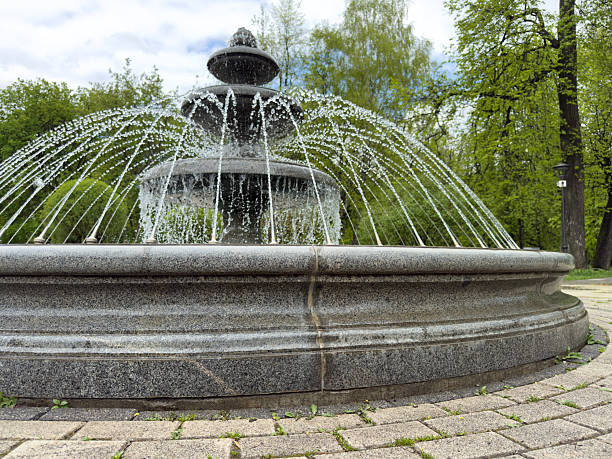 istock Classic round granite fountain with decorative multi-tiered structure and dynamic water jets in urban park environment 2228239023