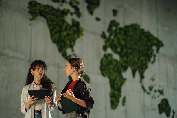 istock Young businesswomen planning global strategy in modern office with moss wall map 2228240429