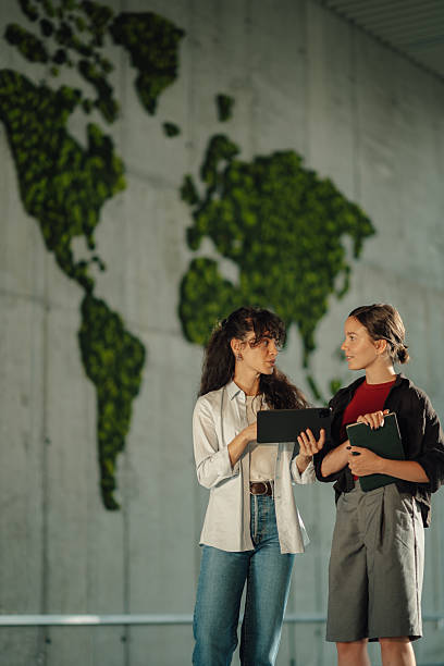istock Two young businesswomen discussing global matters with tablet and world map 2228240432