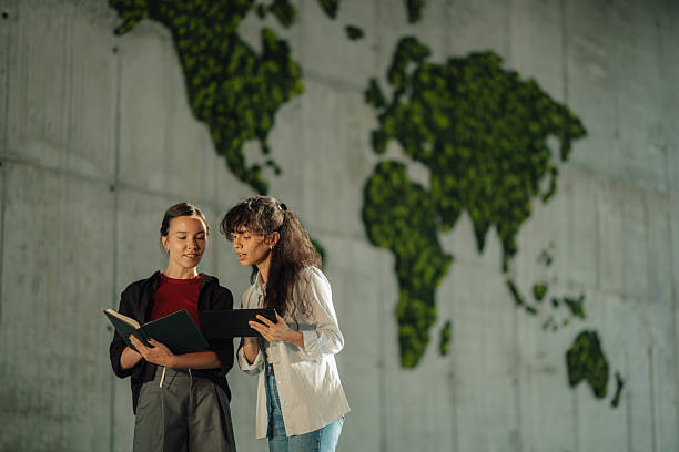istock Two young women discussing global issues near moss world map 2228240442