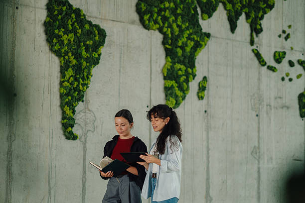 istock Two young businesswomen discussing global environmental issues in front of a moss world map 2228240445