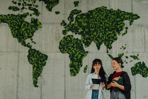 istock Two young women discussing sustainability by a moss world map 2228240451