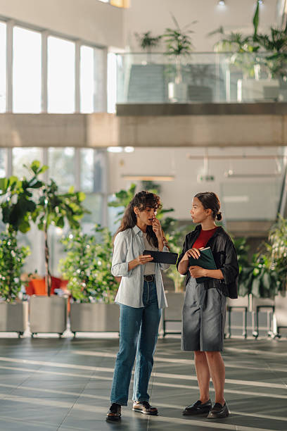 istock Two young female colleagues discussing a project using a tablet in a modern office building 2228240464