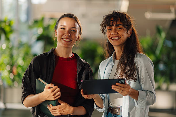 istock Two young businesswomen smiling and holding digital tablet and notebook 2228240475