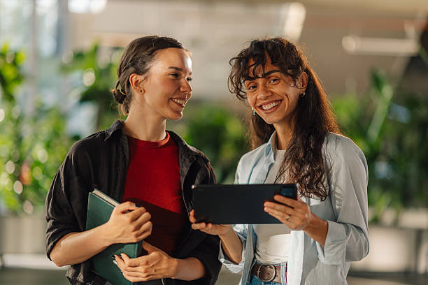 istock Two young businesswomen smiling and using digital tablet in office 2228240488