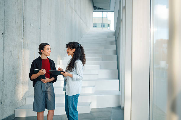 Two young businesswomen discussing using digital tablet in modern office