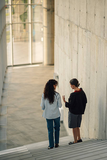 istock Two young adults walking and talking on stairs in modern building 2228240524