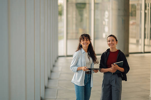 istock Two young businesswomen smiling and holding digital tablet and notebook 2228240530