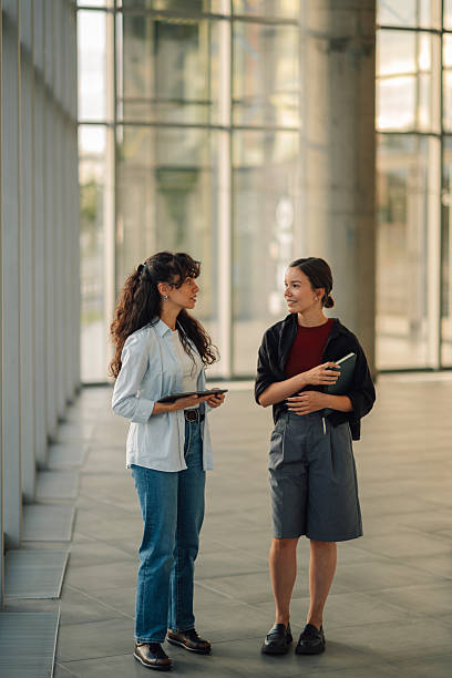 istock Two young businesswomen talking and holding digital tablet and notebook 2228240532