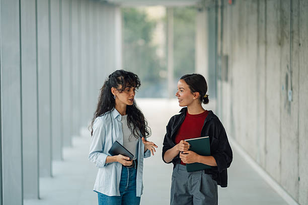 istock Two young female colleagues talking and walking in a modern office building 2228240557