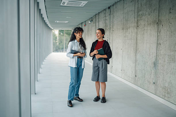 istock Two young female students talking in university corridor 2228240577