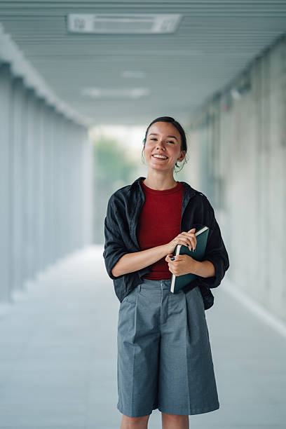 istock Smiling student holding book in university hallway 2228240626