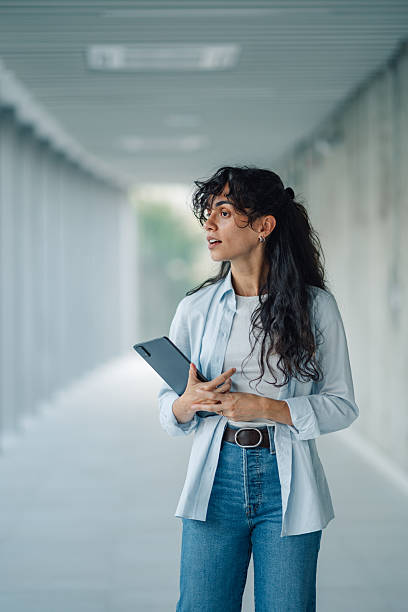 istock Young professional woman holding digital tablet in modern office corridor 2228240631