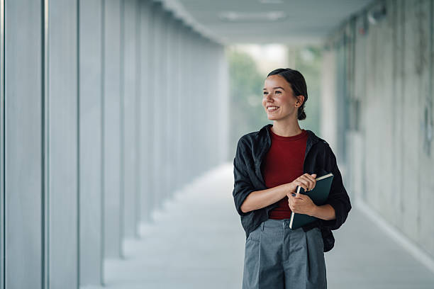 Smiling young woman walking through office hallway holding notebook