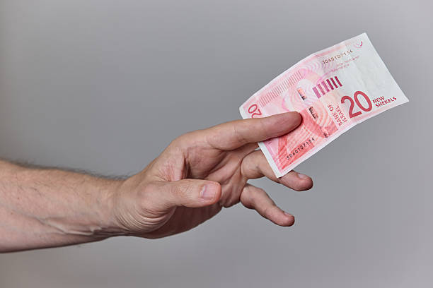 istock Hand Holding Israeli Shekel Banknotes on Neutral Background 2228246026