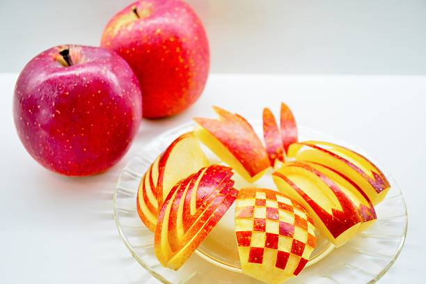 Whole and sliced kissabel apple against white background.