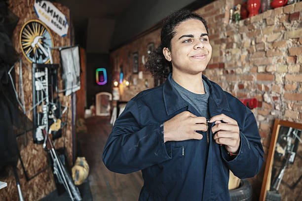Hispanic male teenager getting ready for rage room. He is dressed in protective work clothes with protective helmet. Interior of Rage Room gym in downtown Hamilton, Ontario in Canada.