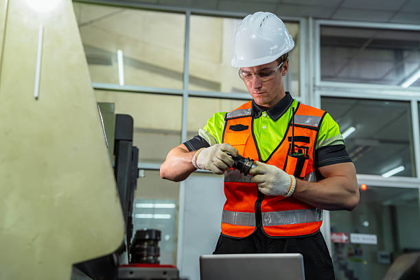 istock A man in a safety vest is working on a machine. Professional engineer engaged in precision manufacturing, preparing tooling and programming an industrial machine in a factory workshop. 2228260702